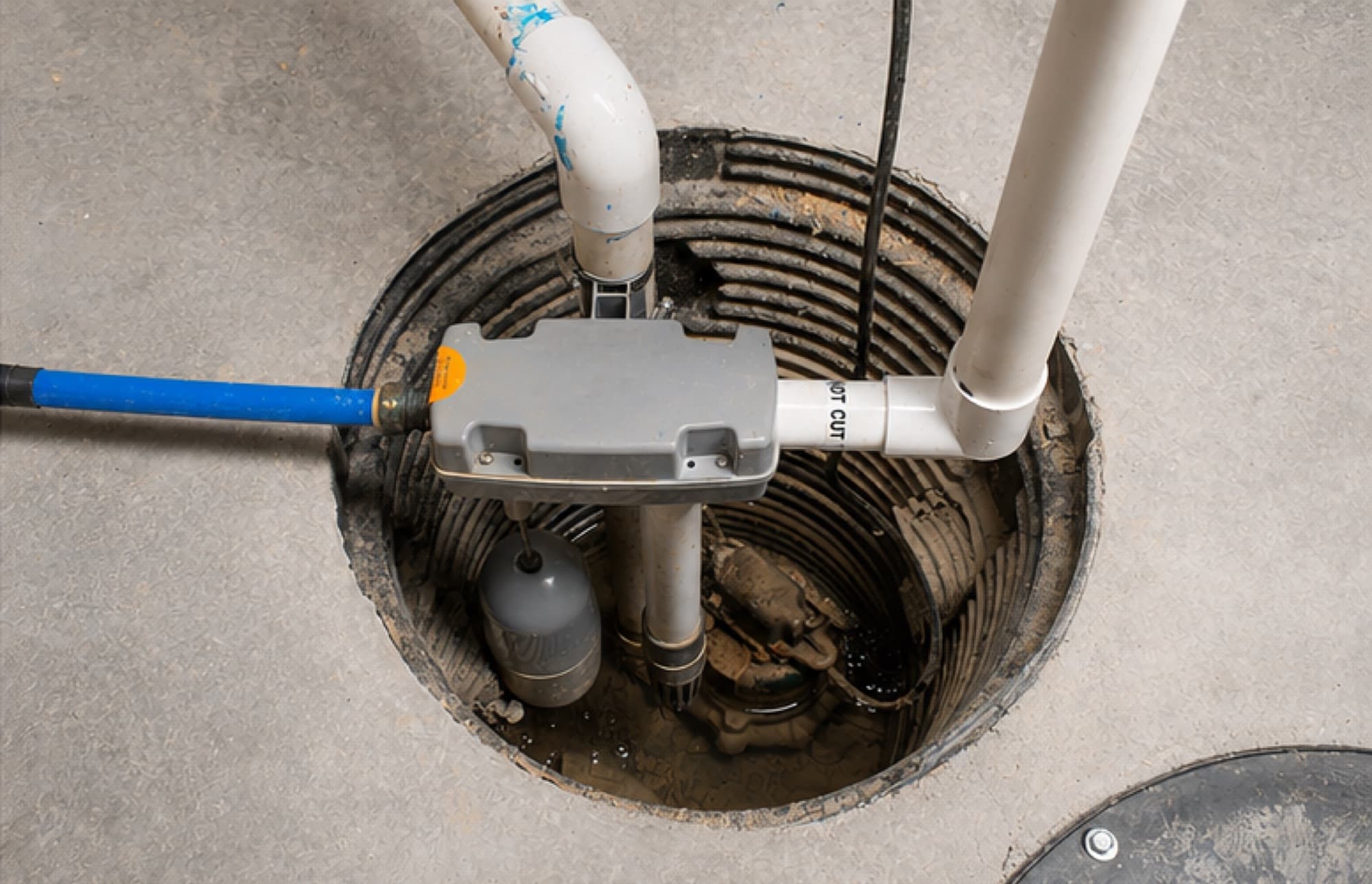A sump pump installed in a basement sump pit with discharge piping